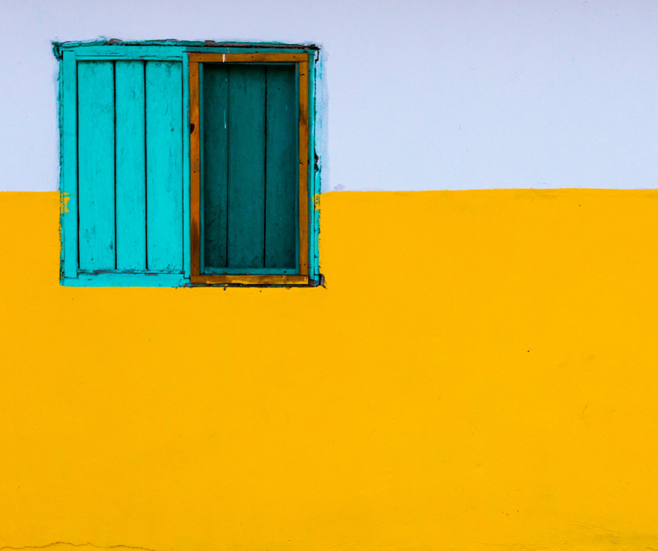 A teal window on a yellow & white wall